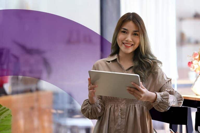 A smiling woman with a tablet looks directly at the camera. Success in an accounting or finance career depends on the ability to communicate reports clearly, among others.